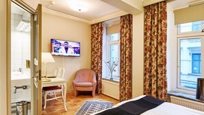 A hotel room with a bed, a chair, a television, and a window with curtains. - Hotel Royal (Gothenburg)