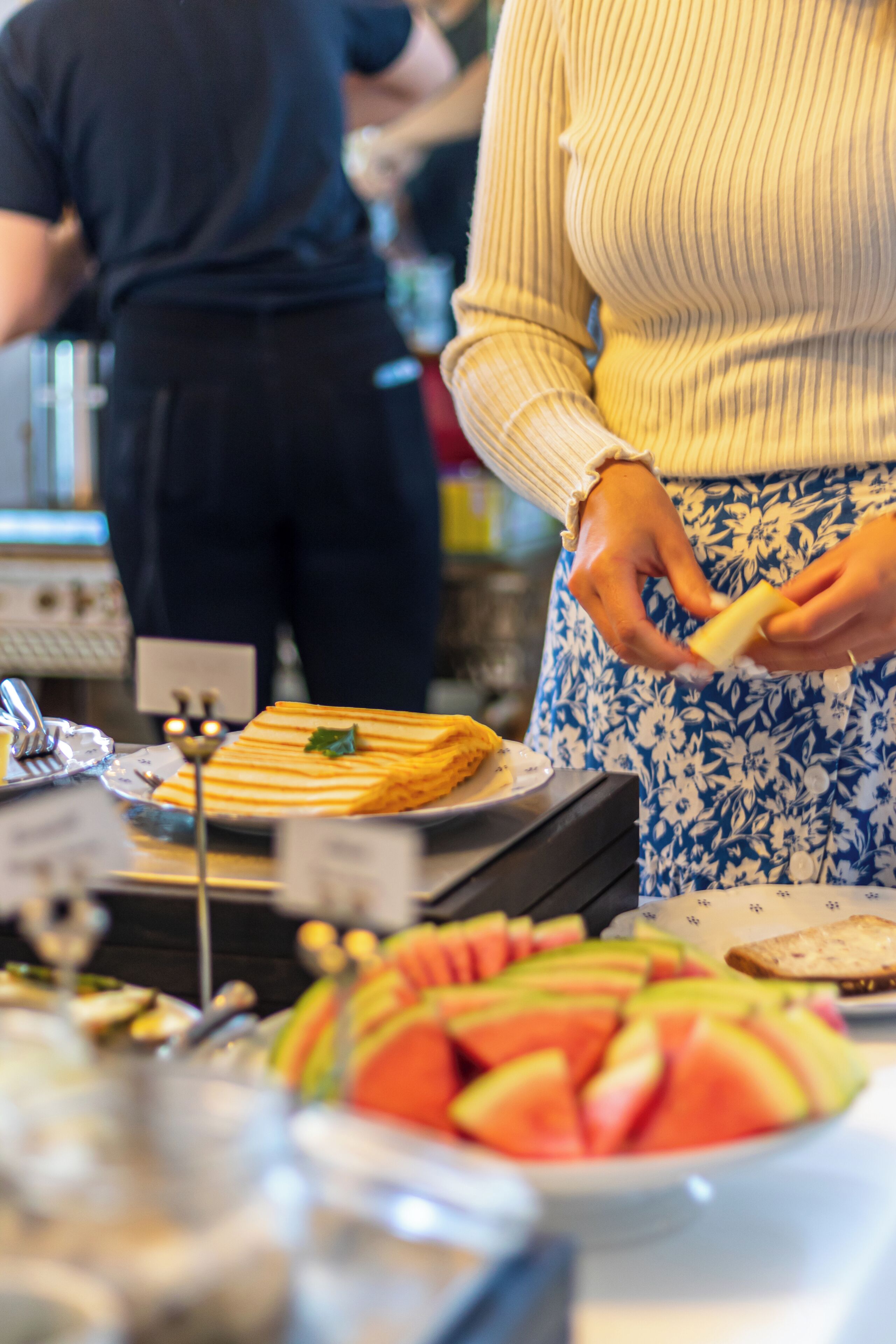 Ein reichhaltiges Buffet mit verschiedenen Speisen, darunter ein Teller mit Wassermelone und eine Pfannkuchenstapel.