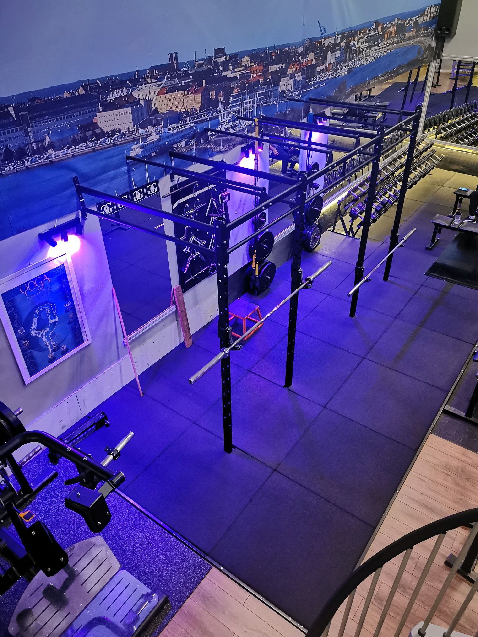 A gym with a variety of exercise equipment, including weight racks and a yoga mat.