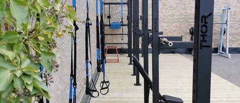 Un gimnasio al aire libre con equipamiento de ejercicio, incluyendo barras de dominadas y estaciones de levantamiento de pesas.