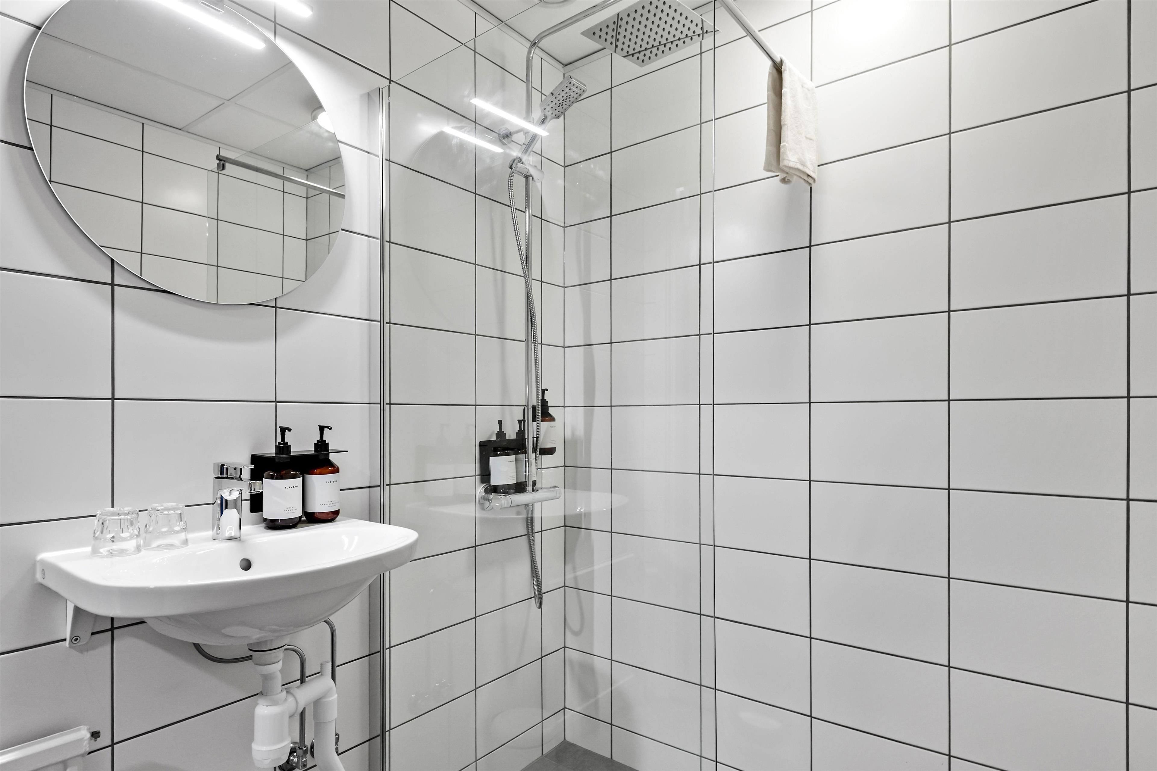 A modern bathroom with a white sink, mirror, and shower.