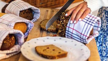 A person cutting bread on a wooden cutting board.