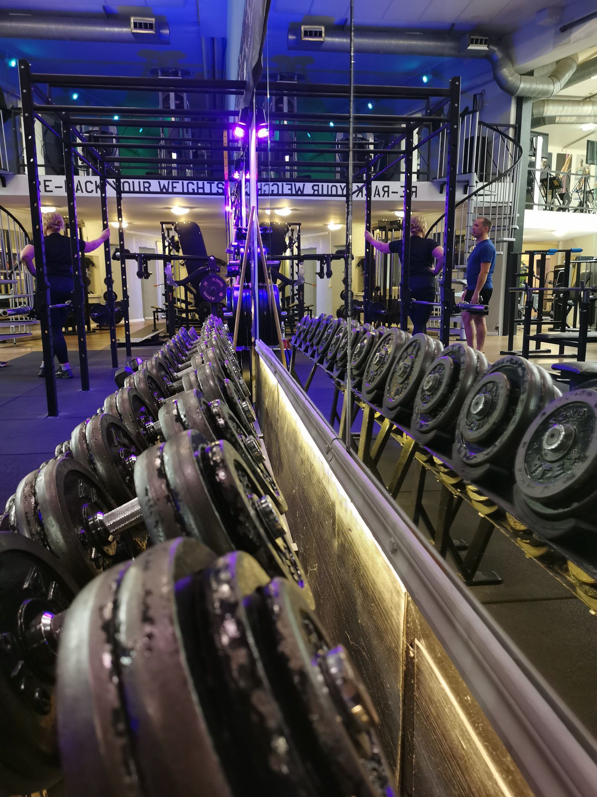 A gym with weightlifting equipment, including dumbbells and barbells.