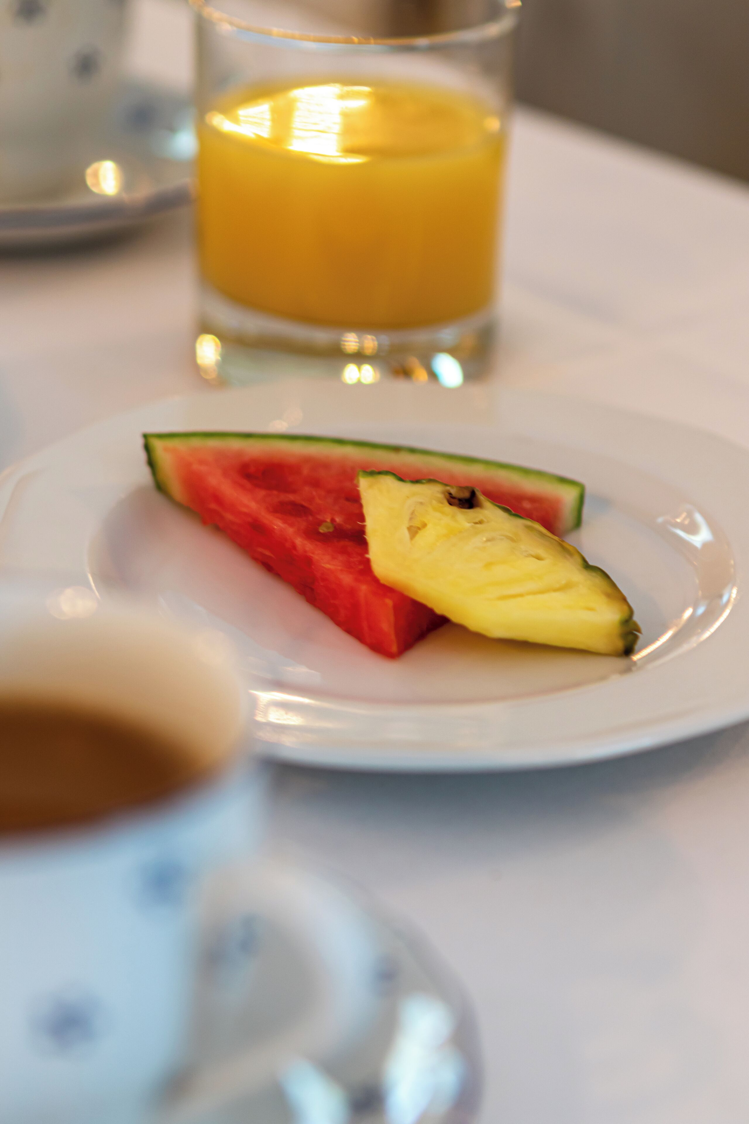 A plate with watermelon and pineapple on a white table.