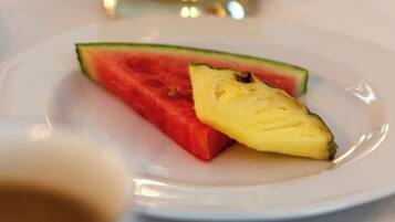 En tallrik med vattenmelon och ananas på ett vitt bord.