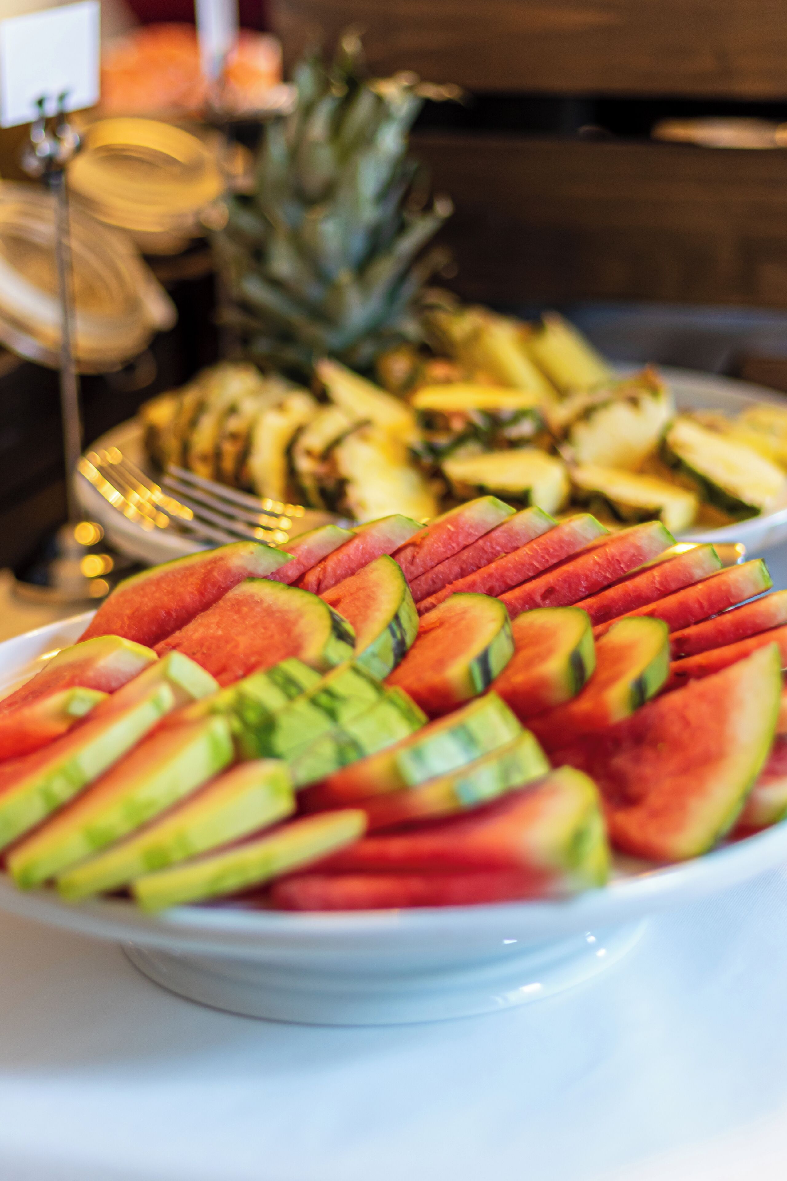 A buffet table with a variety of fruits including watermelon and pineapple.