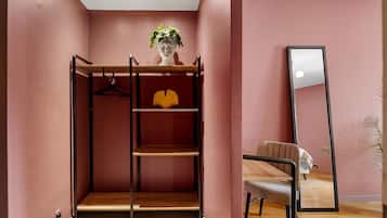 Una habitación con literas, un espejo y una planta.