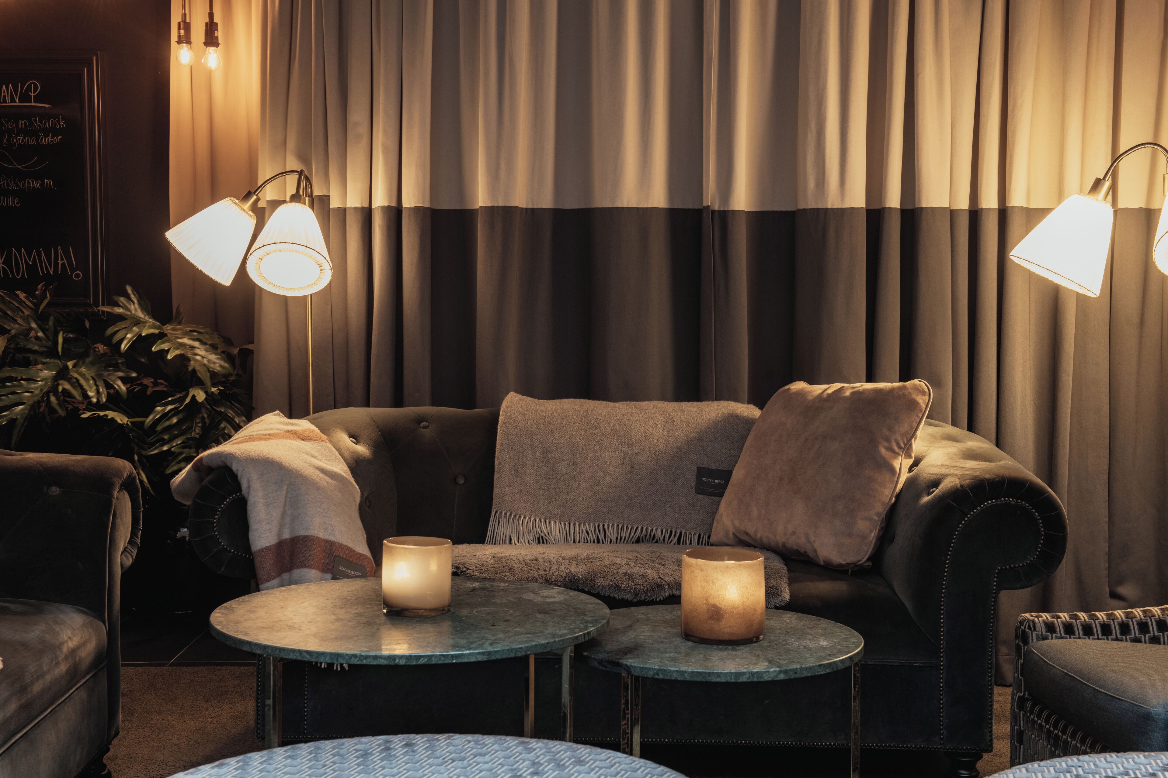 A cozy seating area with a sofa, two small round tables, and two floor lamps.