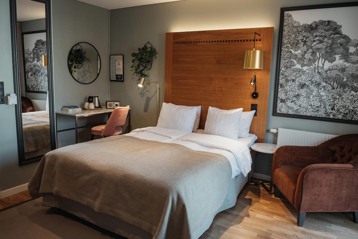 A modern bedroom with a large bed, bedside tables, a desk, and a chair.