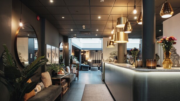 Un moderno vestíbulo de hotel con mostrador de recepción, zona de estar y amplios ventanales.