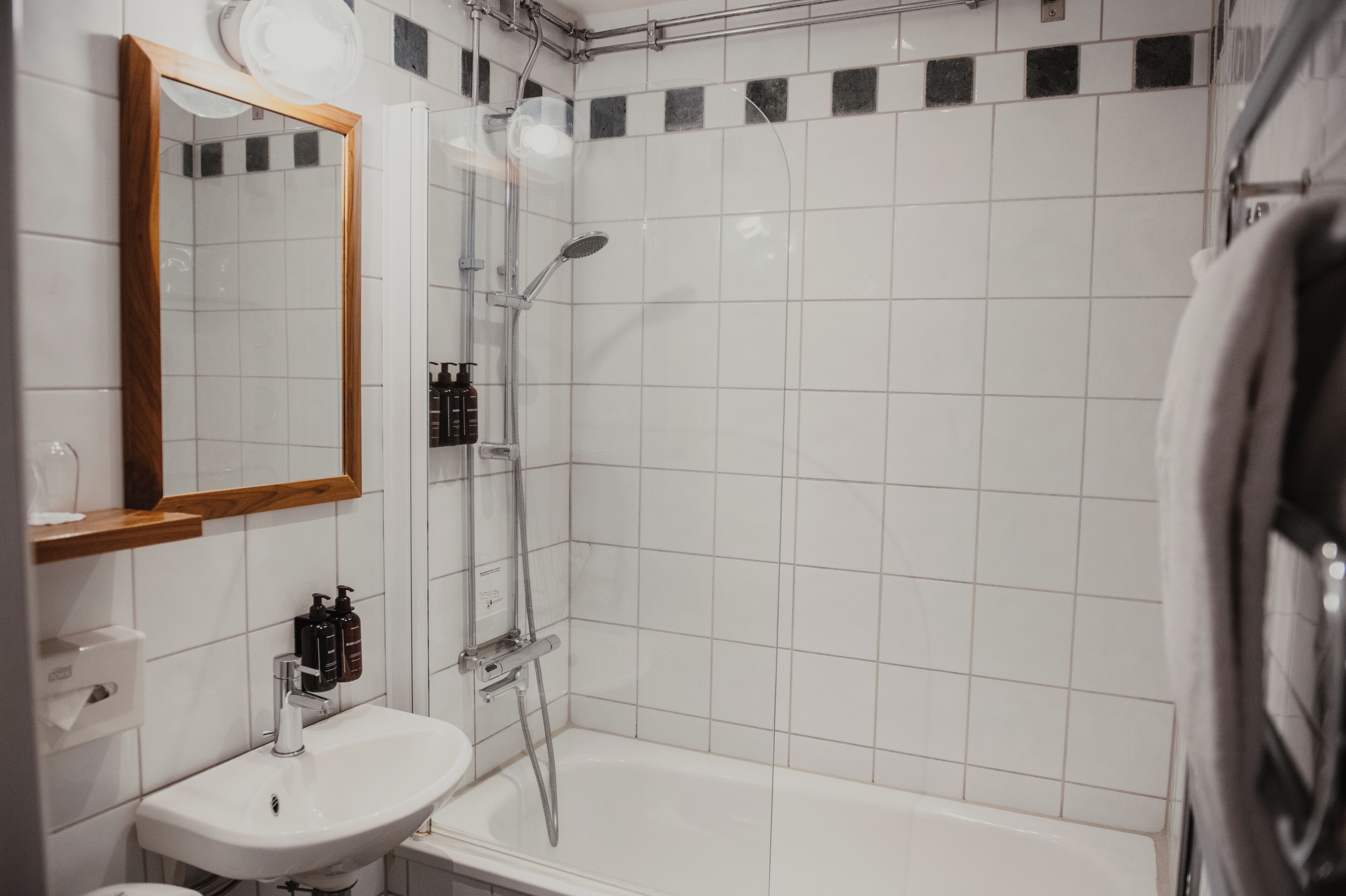 Un baño con lavamanos, espejo y ducha blancos.