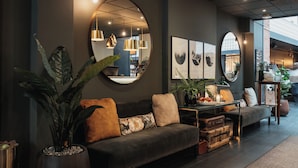 Un interior moderno con un sofá gris oscuro, espejos redondos e iluminación colgante.
