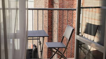 Un balcon avec une balustrade en métal, une petite table et une chaise.
