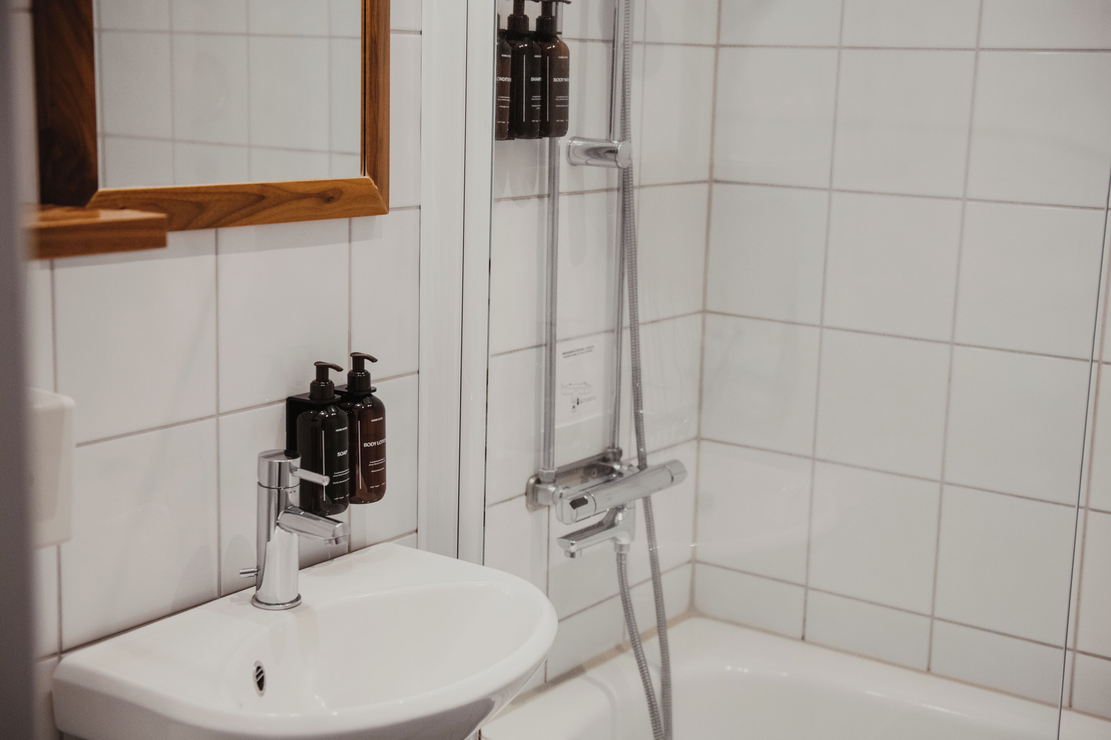 Un baño con un lavabo blanco, un espejo y una cabina de ducha.