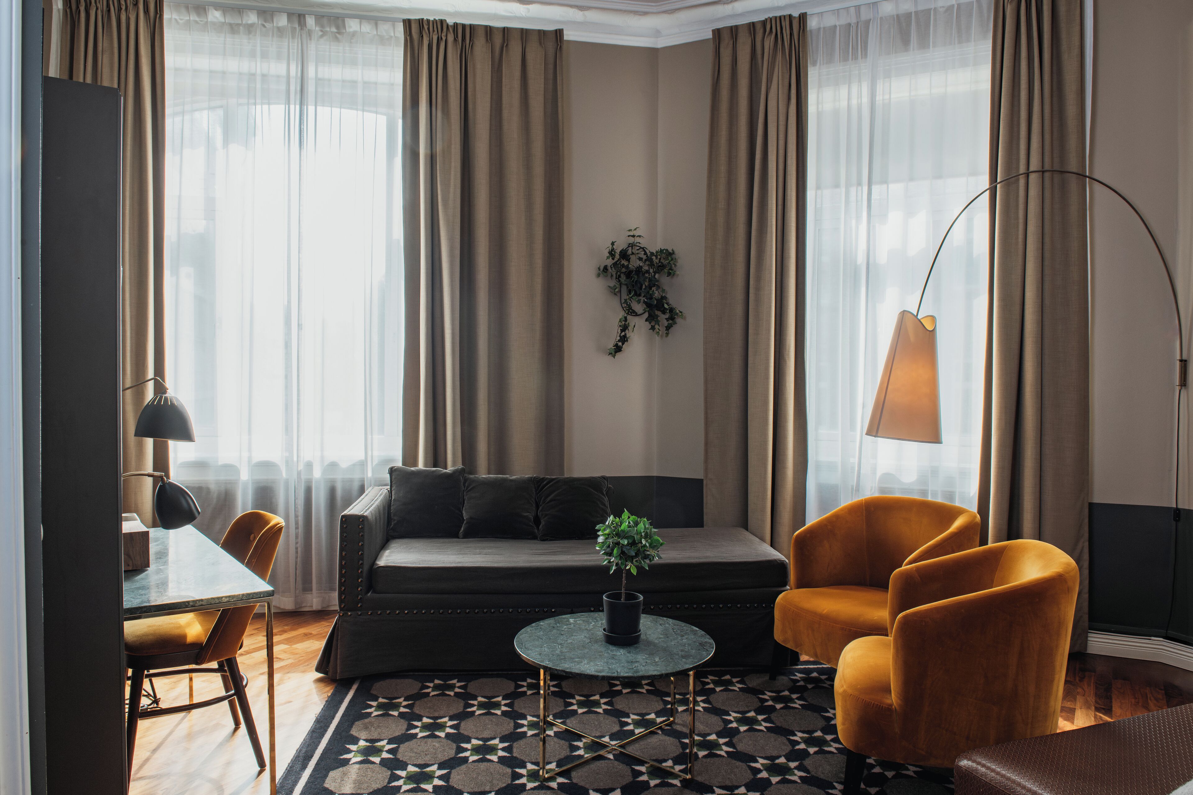 A modern living room with a sofa, two armchairs, a coffee table, and a dining area with a table and chairs.