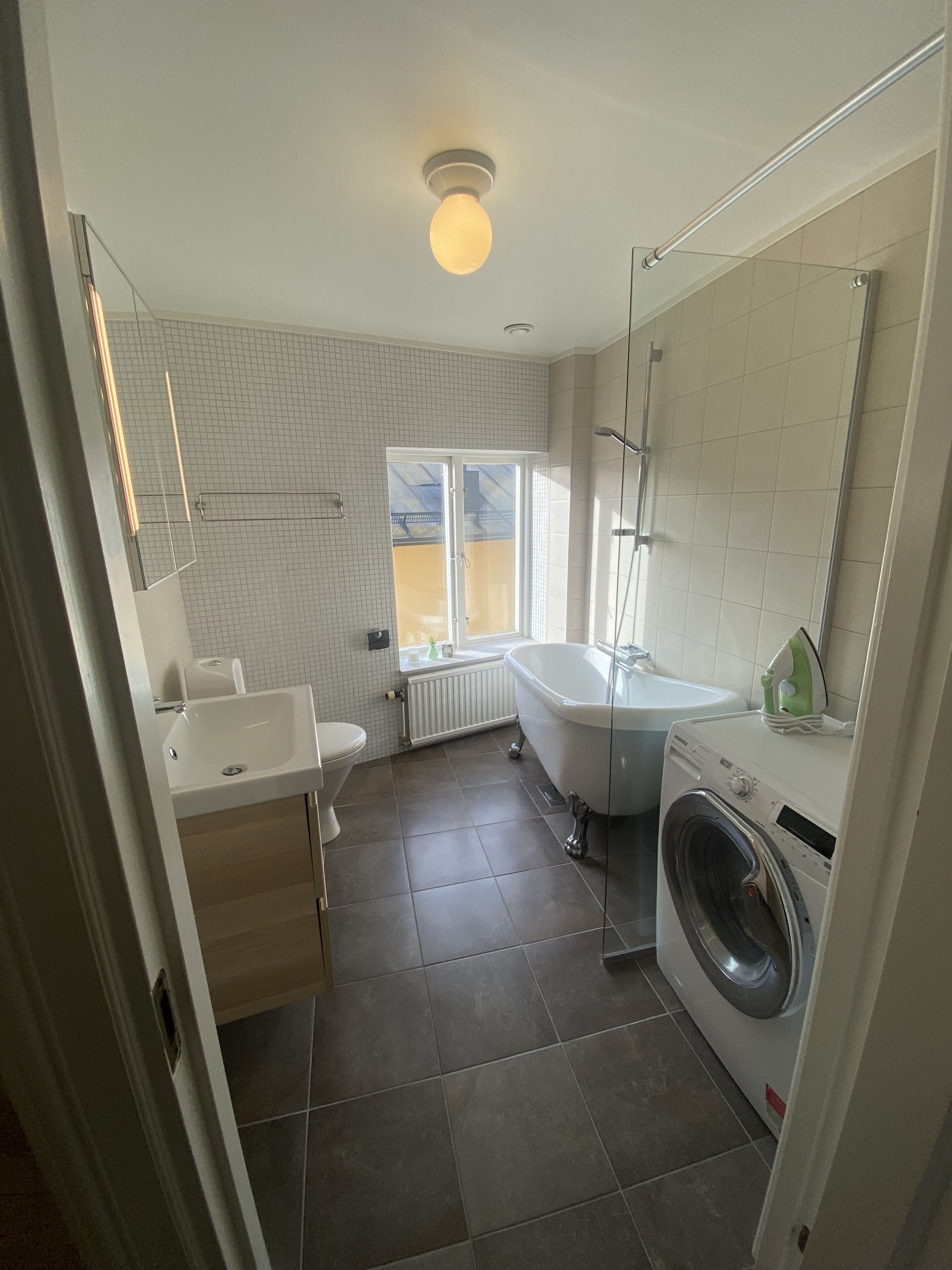 Ein modernes Badezimmer mit Badewanne, Waschmaschine, Waschbecken und Toilette.