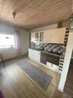 Una cocina moderna con techo de madera, armarios blancos, salpicadero de azulejos y horno empotrado.