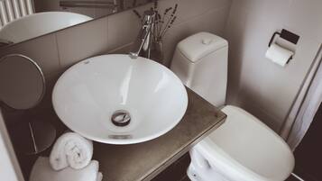 A bathroom with a white sink, a toilet, and a mirror.
