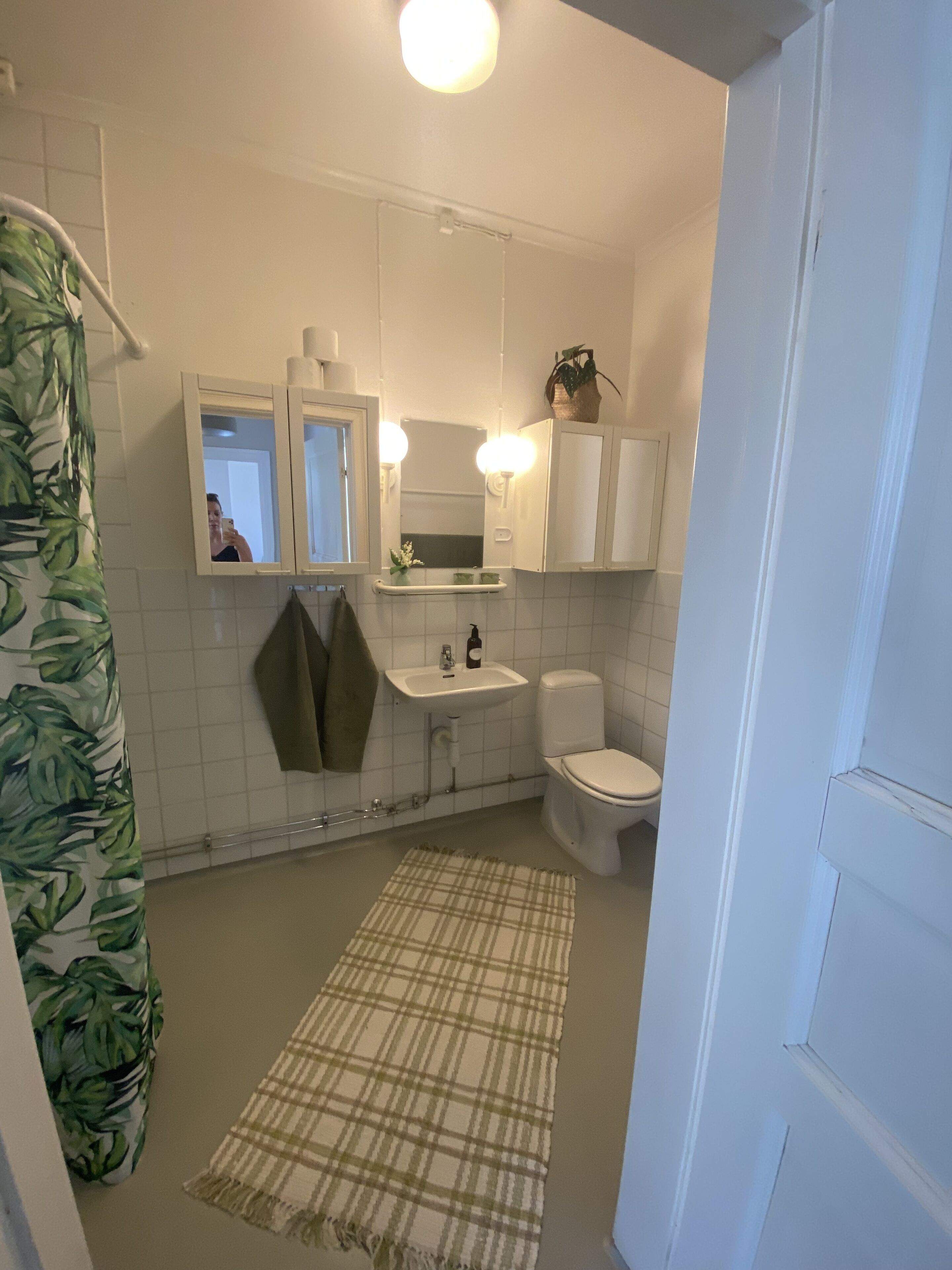 A bathroom with a shower, toilet, sink, and mirror.