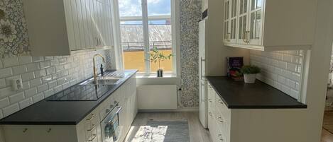 A modern kitchen with white cabinetry, a black countertop, and a view of the outside.