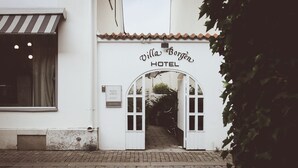 The entrance to Villa Borgen Hotel with a tiled roof and a sign above the door.