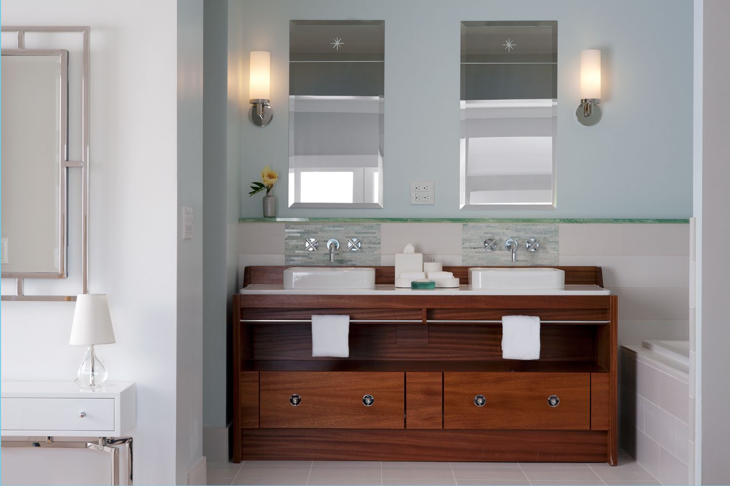 Un baño moderno con tocador de madera, dos lavamanos y un espejo grande.