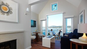 A spacious living area with a fireplace, a dining table, and a seating area with a view of the marina.