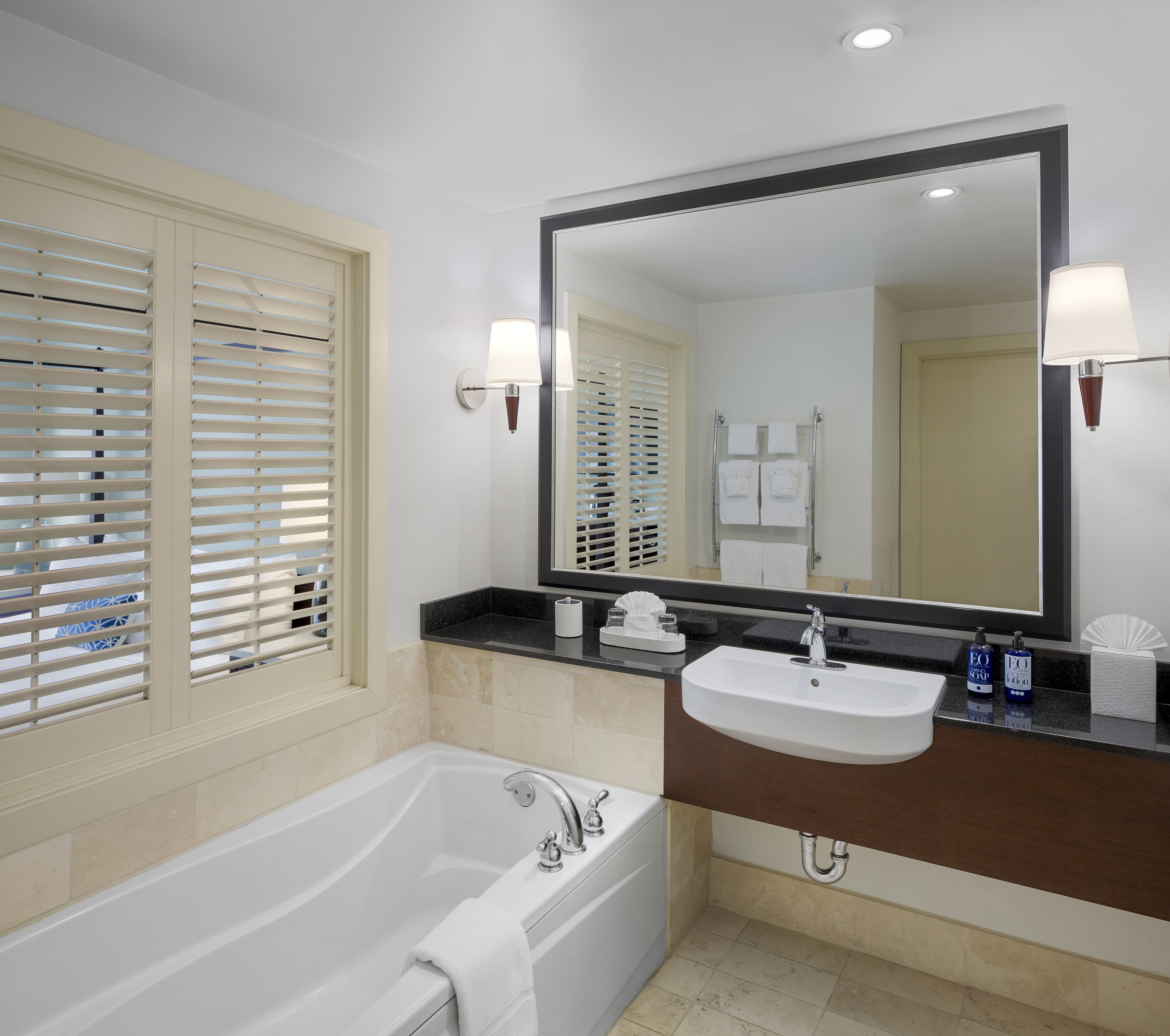 Un baño moderno con bañera, lavamanos y un espejo grande.
