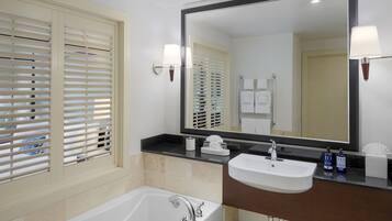 Un baño moderno con bañera, lavamanos y un espejo grande.