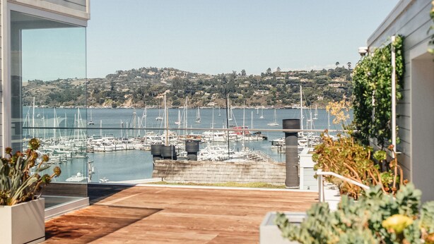 A modern patio with a view of a marina and hills in the distance.