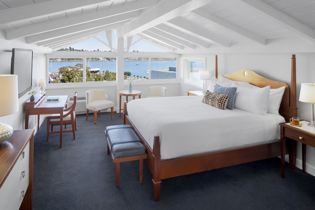 Ein Schlafzimmer mit einem großen Bett, einem Schreibtisch, einem Stuhl und Meerblick.