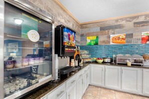A self-service breakfast station with a variety of food items, a digital clock, and a menu board.