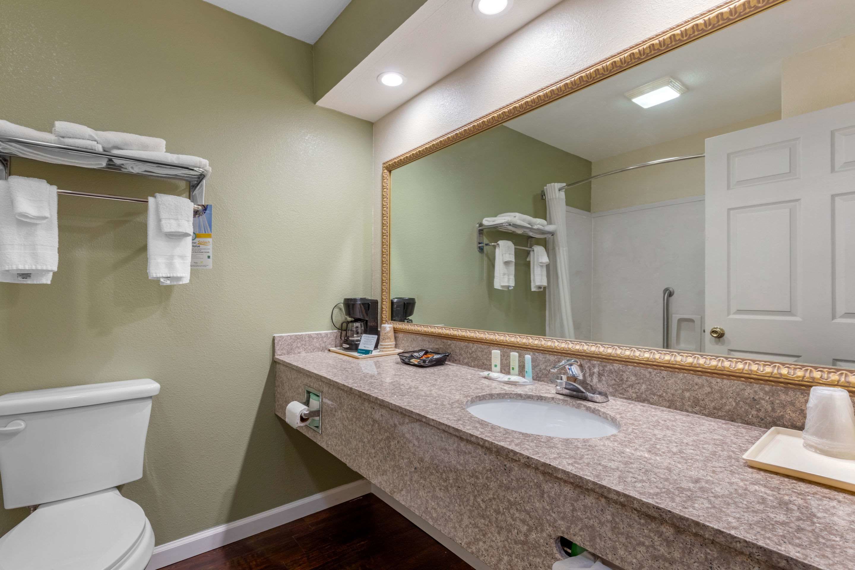 A bathroom with a sink, mirror, towel rack, and toilet.