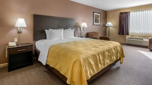 A hotel room with a large bed, two bedside tables with lamps, a chair, a desk, and a window with curtains. - Quality Inn West Memphis I-40 (West Memphis)