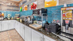 A modern kitchen with white cabinets, a granite countertop, a coffee machine, a microwave, and a bread machine. - Quality Inn West Memphis I-40 (West Memphis)