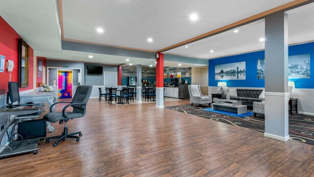 A spacious lobby with a wooden floor, seating areas, a reception desk, and a television. - Quality Inn West Memphis I-40 (West Memphis)