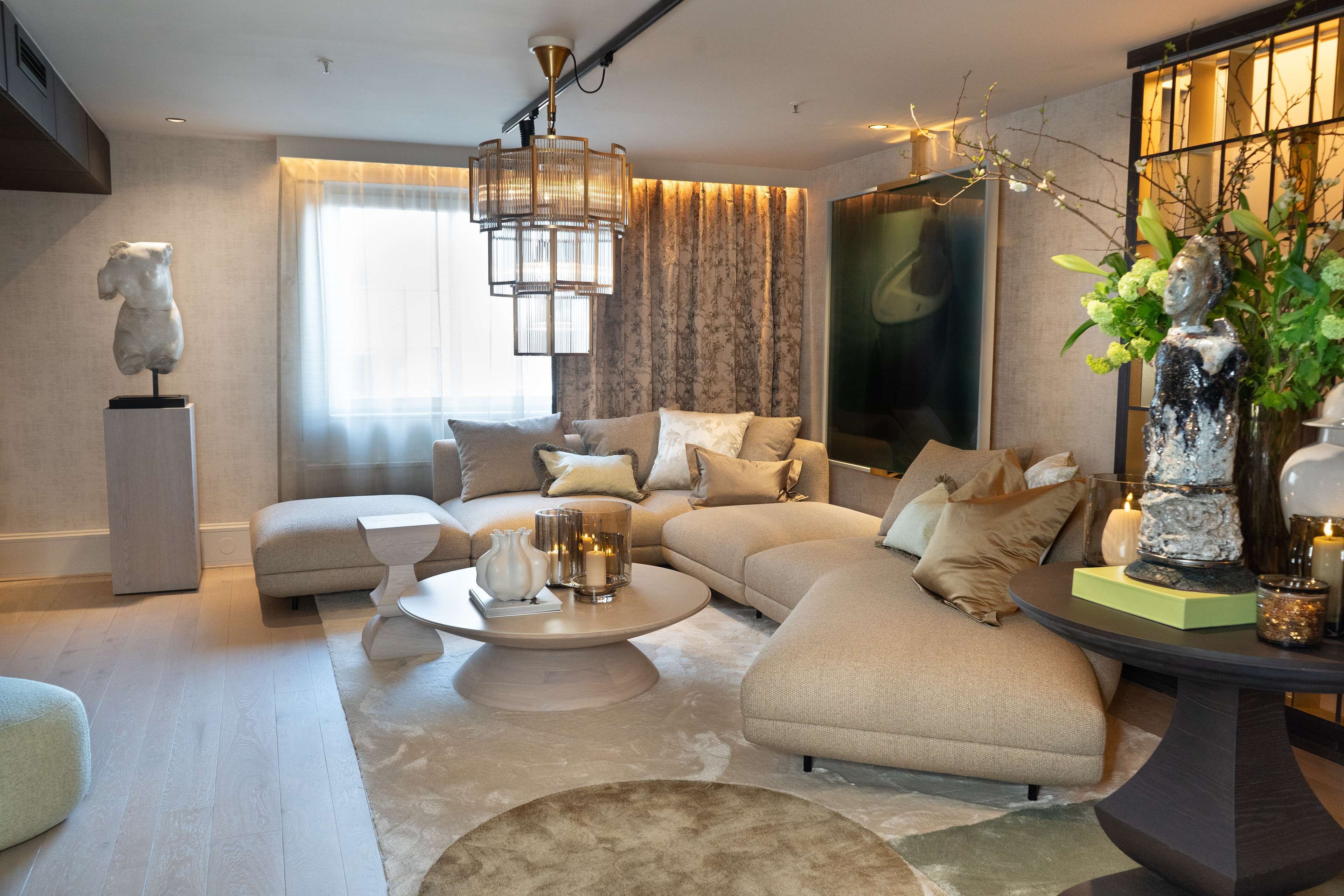 A modern living room with a sectional sofa, a round coffee table, and decorative vases.