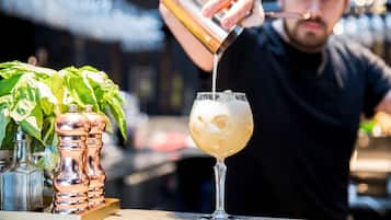A bartender pouring a drink into a glass.