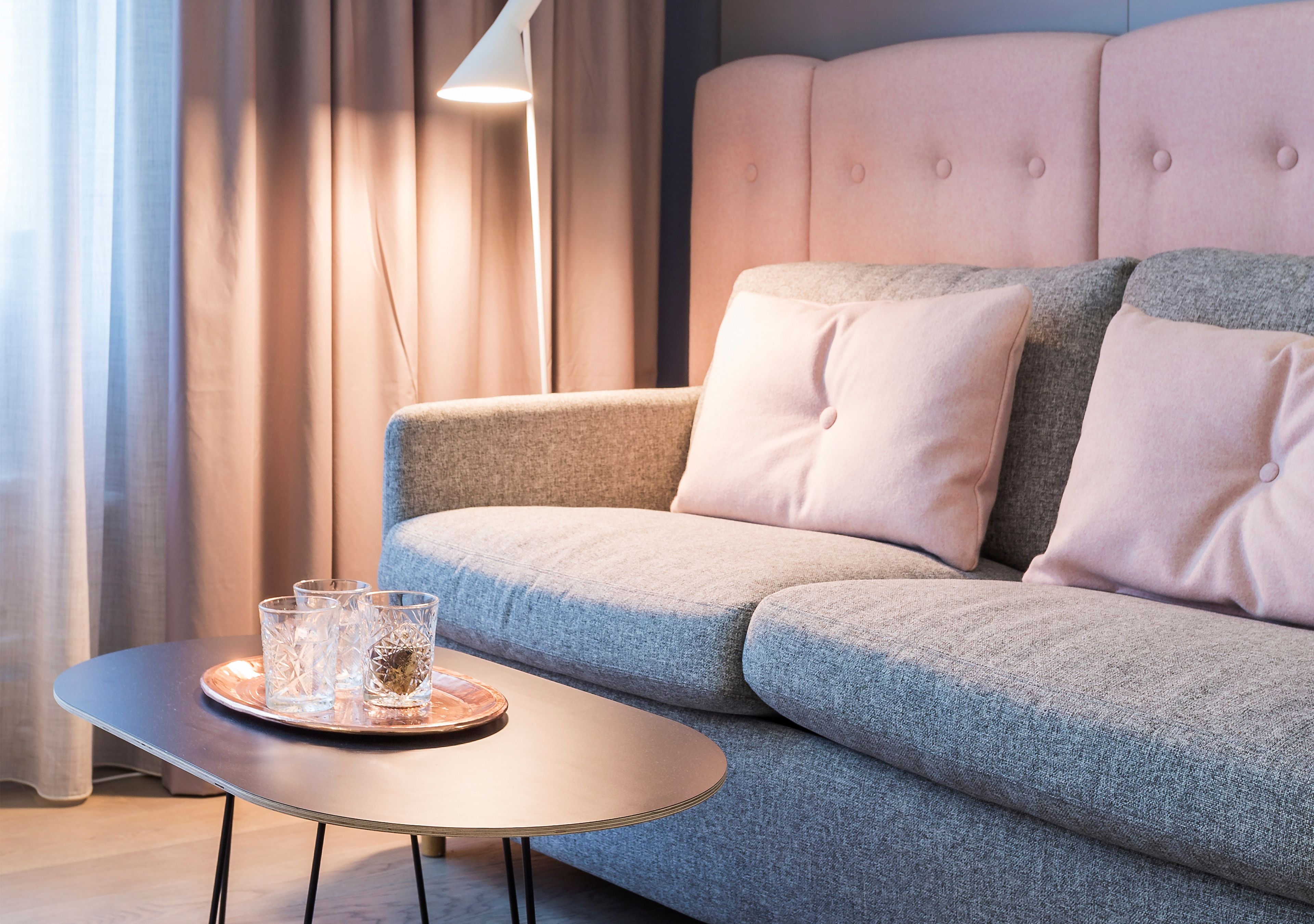 Ein modernes Wohnzimmer mit einem grauen Sofa, einem kleinen runden Tisch und einem Tablett mit zwei Gläsern.