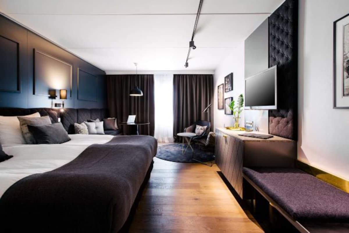 Una habitación de hotel moderna con una cama grande, un escritorio, una silla y un televisor.
