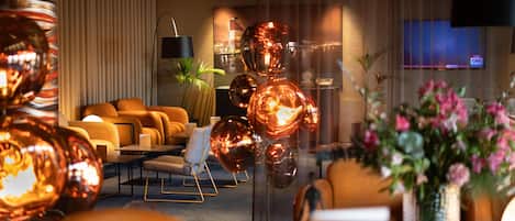 A modern hotel lobby with a sofa set, a plant, and decorative glass spheres.
