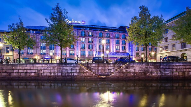 A hotel with a stone facade, multiple windows, and a reflection in the water. - Radisson Blu Scandinavia Hotel (Gothenburg)