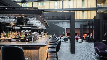 A bar area with a long counter, multiple stools, and a variety of bottles and glasses.