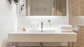 Une salle de bain moderne avec un grand miroir, un lavabo blanc et une cabine de douche en verre.