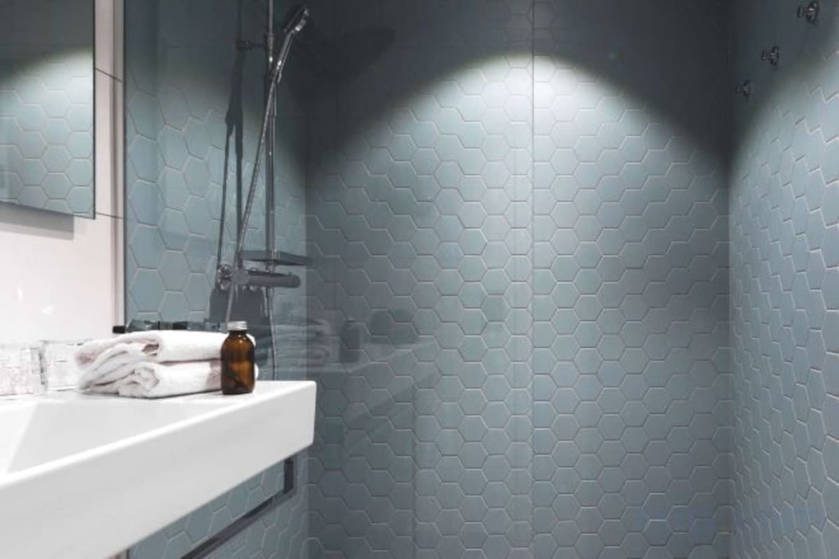 A bathroom with a white sink, a mirror, and a shower area.