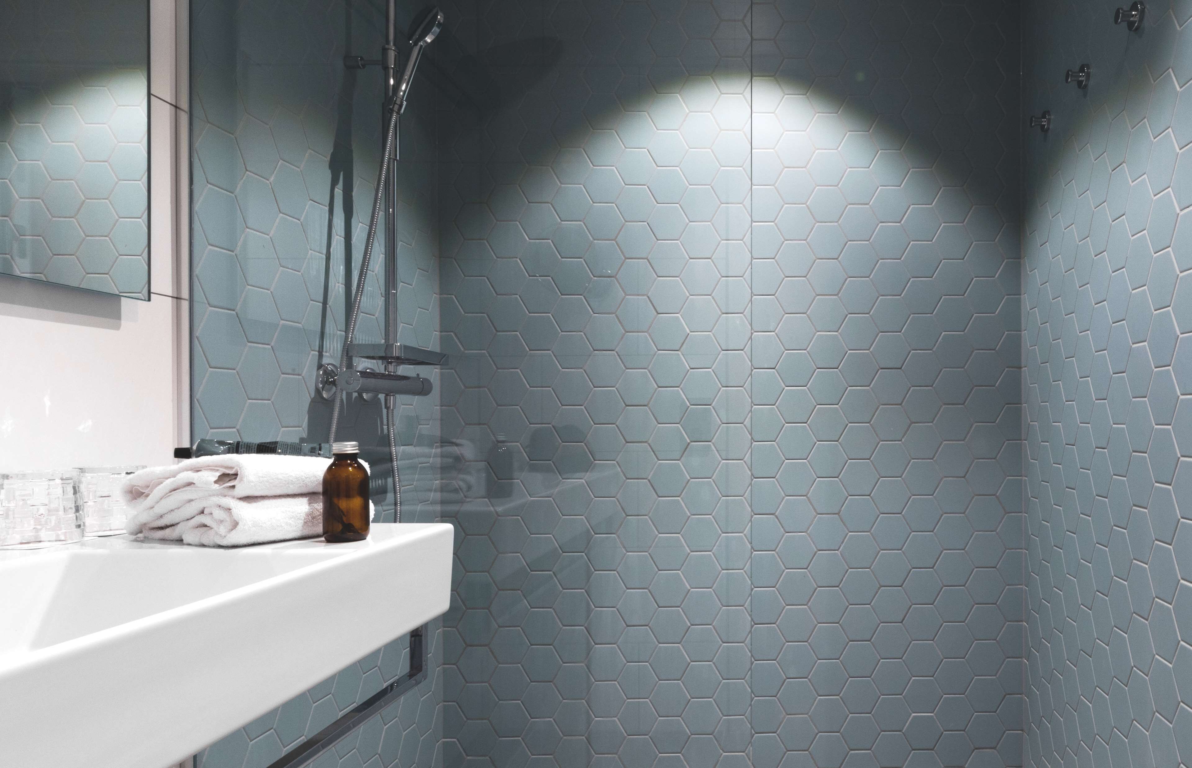 A bathroom with a white sink, a glass shower enclosure, and a hexagonal tile pattern on the walls.