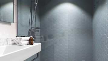 A bathroom with a white sink, a glass shower enclosure, and a hexagonal tile pattern on the walls.