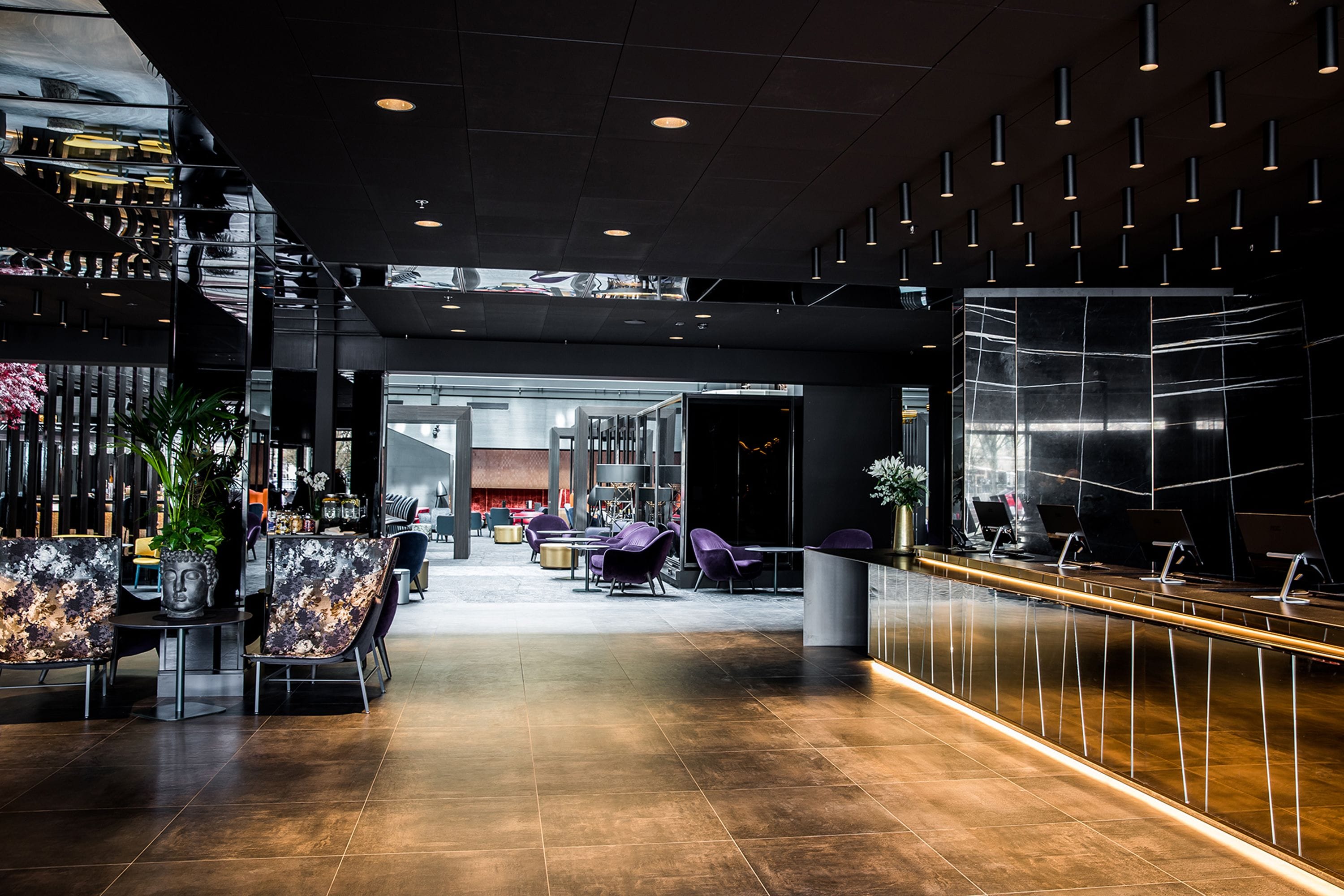 En moderne lobby med reception, siddeområde og bar.