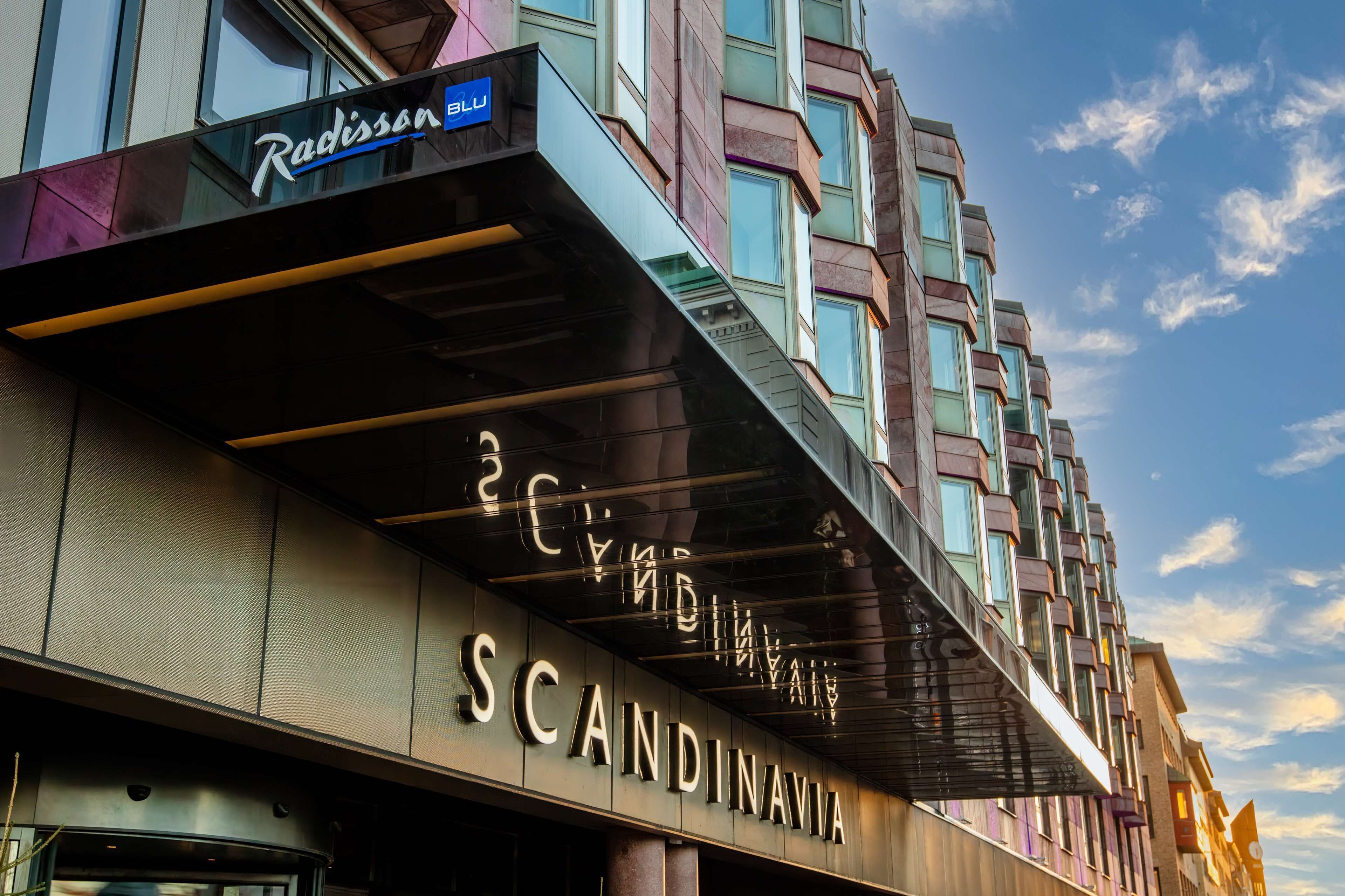Un hotel con fachada moderna, que incluye un letrero destacado de 'Radisson Blu' y 'Escandinavo'.