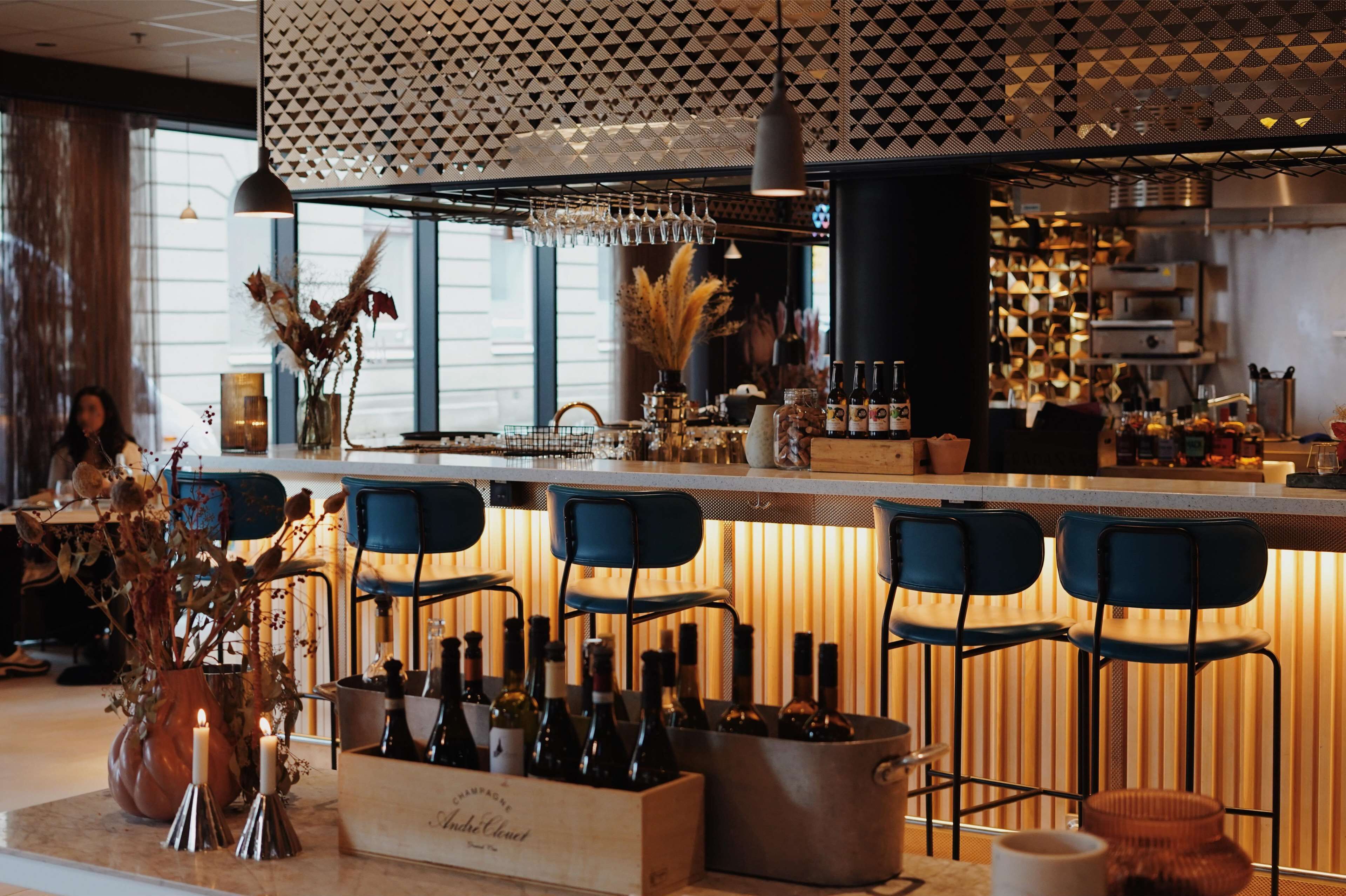A bar area with a modern design, featuring a bar counter, seating, and a variety of bottles.